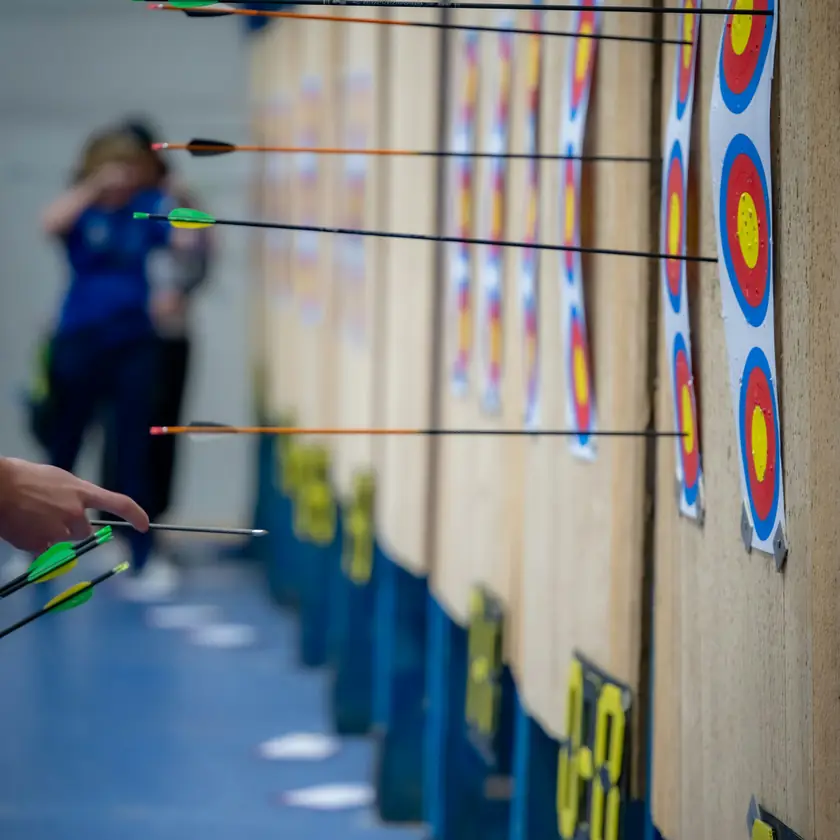 Zielscheiben in einer Sporthalle, Pfeile stecken in den Auflagen
